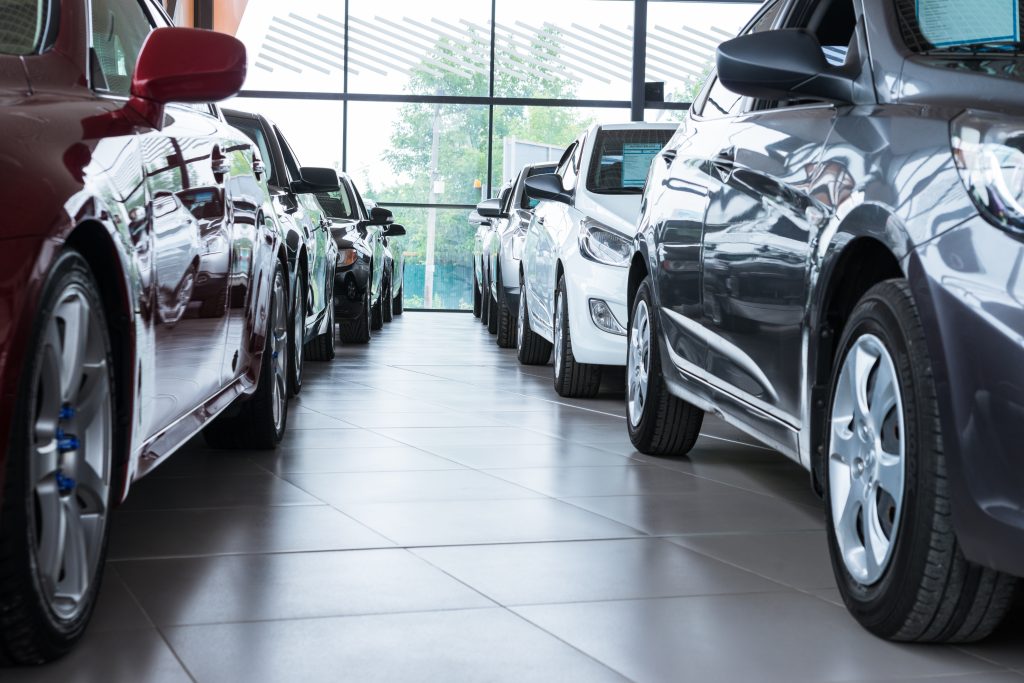 A row of cars displayed in a car dealership showroom.