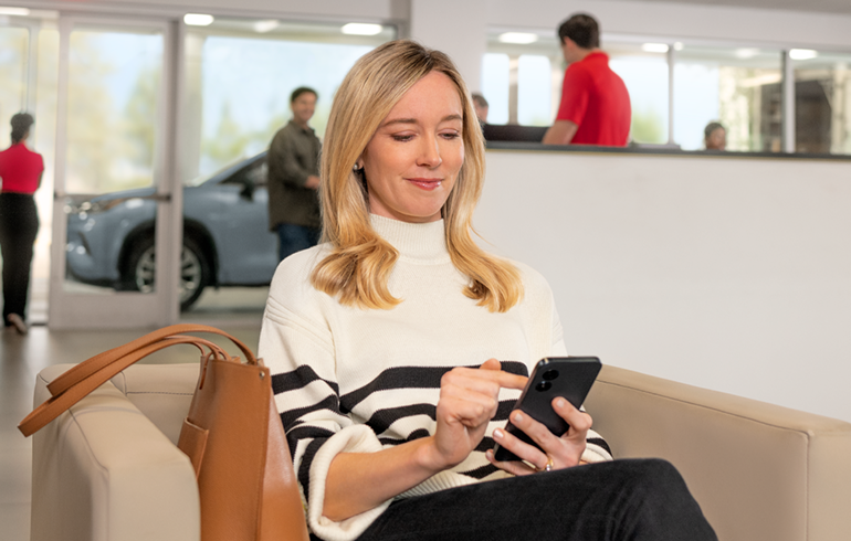 A women is operating mobile at Fitzgerald Toyota Gaithersburg Service center Waiting Room